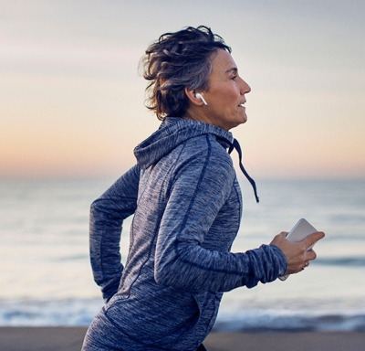 Mature woman listening to music while running along the beach