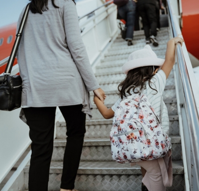 Asian mother holding her daughter's hand while walking up steps to board a plane