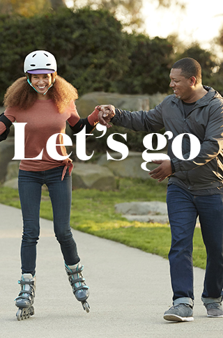 African-American husband helping wife learn to rollerblade
