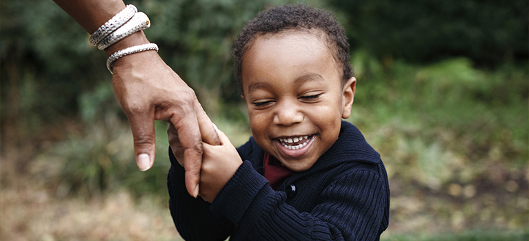 African-American boy holding hand of mother in park