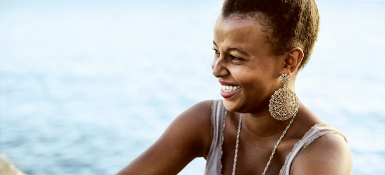 Young woman sitting by the water smiling