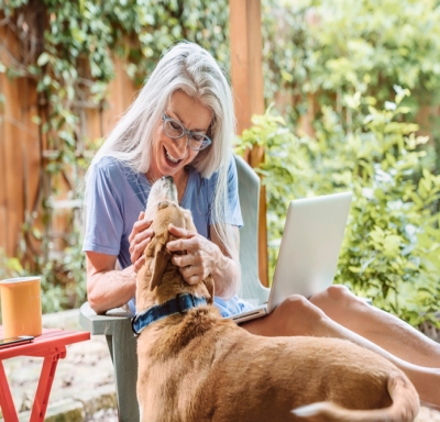 Woman pets her dog while sitting outside at her house
