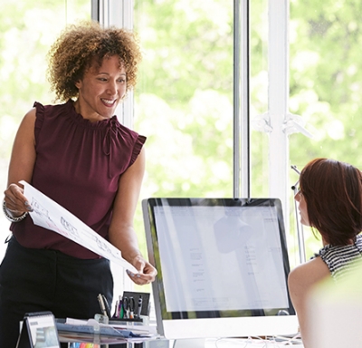 Colleague shows a printout to another colleague in an office setting