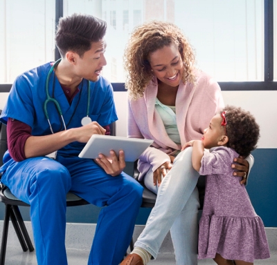 Medical professional explaining information on a tablet to a smile mother and daughter.