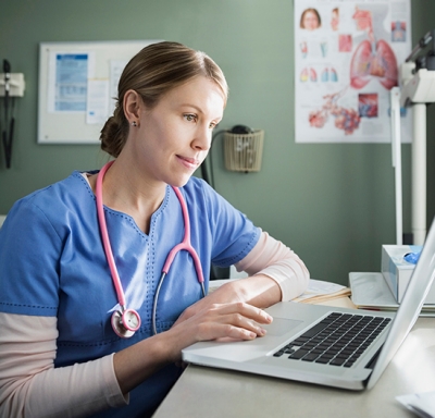 Nurse using a laptop at desk in doctors office
