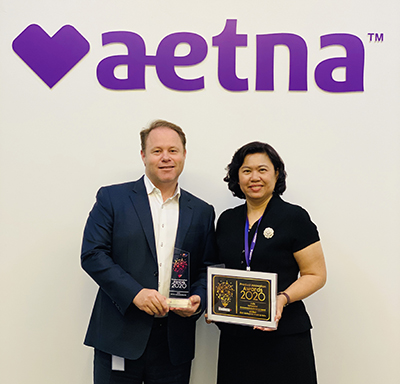 Damian J Delaney and Phatharaporn Teinwan of Aetna pose with Aetna International's 2020 Business+ Best Product Innovation Award 