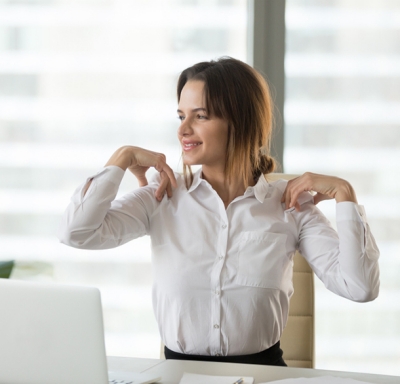 Smiling businesswoman stretching to relieve back and neck tension