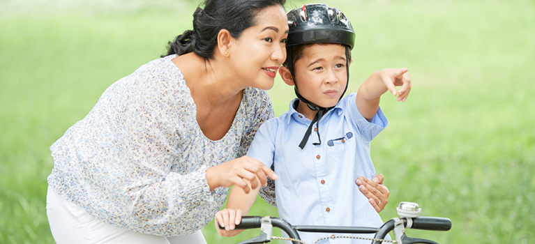 Young Korean boy on bike with doting mother