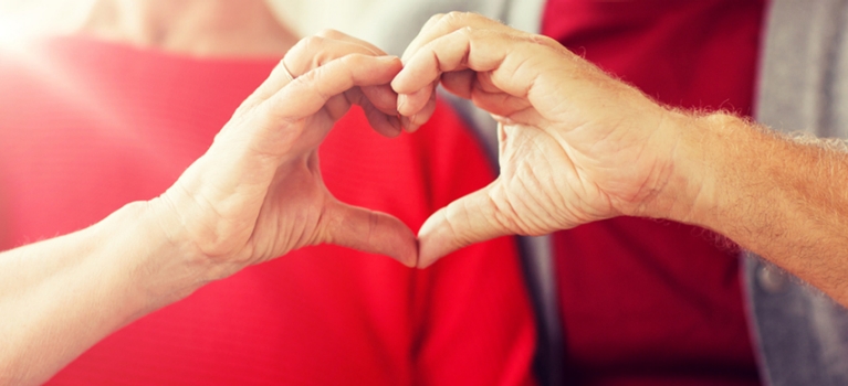 Middle-aged couple forming heart symbol together with their hands