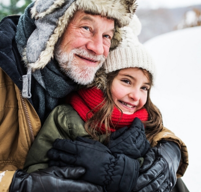 Grandfather and granddaughter outside on a snowy day