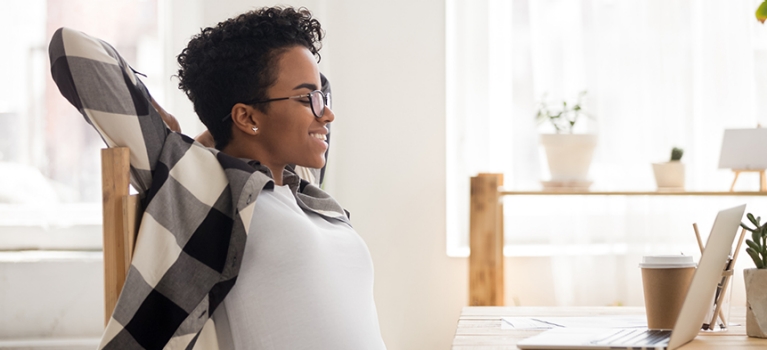 African American woman in office stretching her back. 