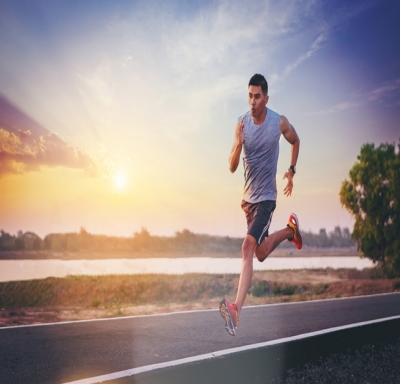Athletic man sprinting on road alongside water