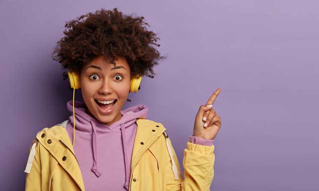 Millennial hipster girl with Afro hair enjoys music podcast in headphones