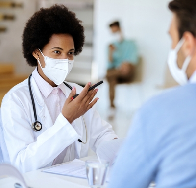 Doctor wearing a mask offering an explanation to her mask-wearing patients