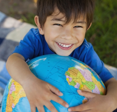 Young boy standing in a park and hugging a globe