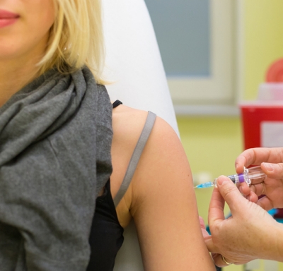 Medical professional giving a female a flu shot in her left arm