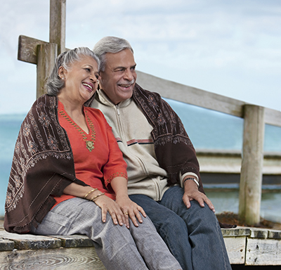 Older couple snuggled together while sitting on a dock overlooking water