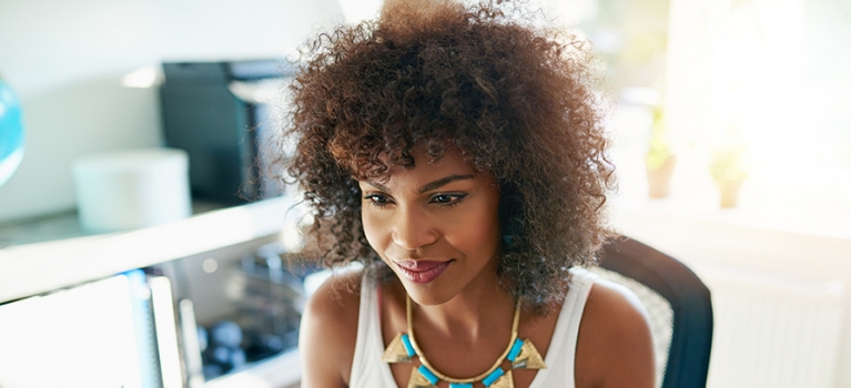 African-American woman smiling while working on computer