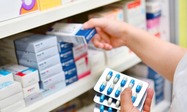Pharmacist placing prescriptions on pharmacy shelf