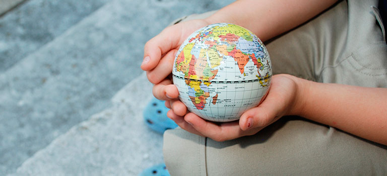 Child sitting on steps holding small globe