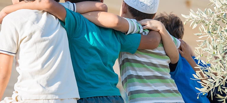 Four multi-cultural boys embracing each other as friends