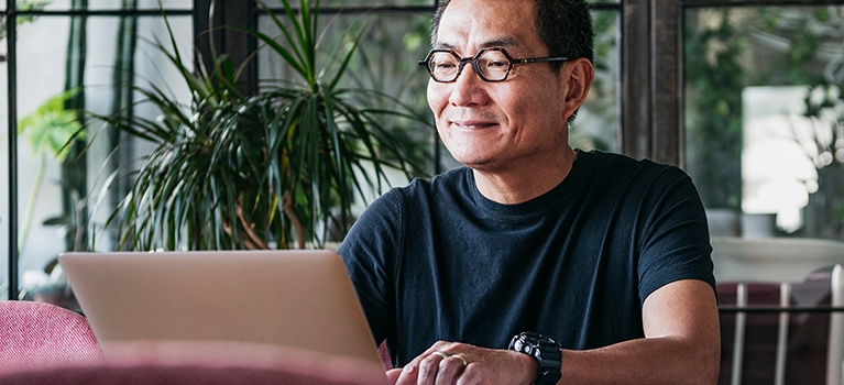 Man smiling while working on laptop.