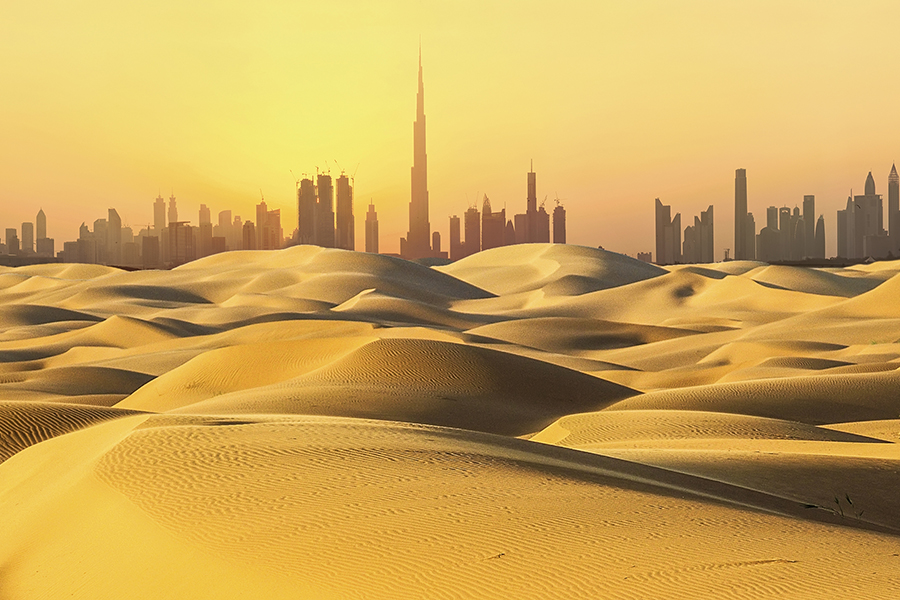 Dubai skyline with skyscrapers, at sunset, viewed from the surrounding desert.