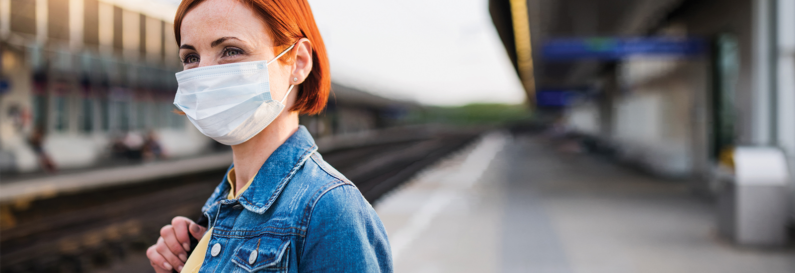 Woman waiting for a train and wearing a face mask to protect herself and others